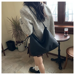 Grand sac hobo en cuir noir avec bandoulière réglable dans un cadre de café chaleureux