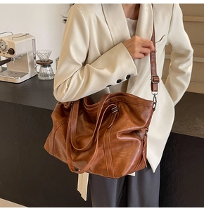 Macro detail of the vintage brown PU leather texture and reinforced metal rivets on the tote bag