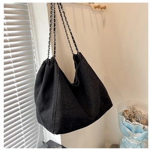 Detailed view of the large denim tote bag with silver chain and leather strap