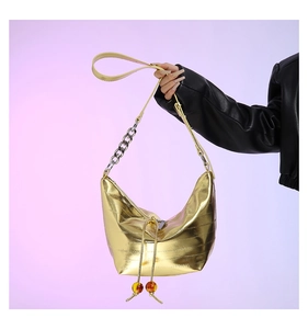 Detalle de bolso hobo dorado metalizado con cuentas de ámbar y correa de cadena mixta