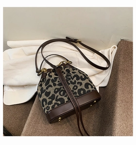 Detail of leopard print bucket bag with brown leather trim and golden metal feet