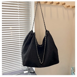 Detail of black denim tote bag with thick silver chain strap and gathered texture