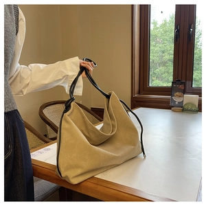 Gros plan d'un sac cabas kaki avec anses noires posé sur une surface en marbre poli