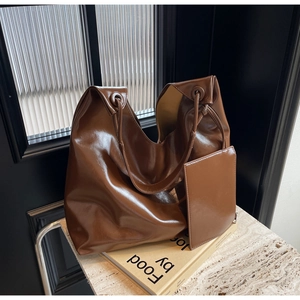 Macro shot of large dark brown glossy leather tote bag with unique circular handle eyelets