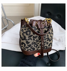 Detail of leopard print bucket bag with leather trim and gold hardware drawstring closure