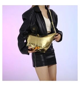 Detalle de bolso medialuna dorado con cordón y cuentas de ámbar en chaqueta de cuero