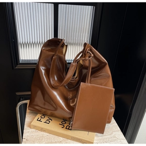 Detail view of the caramel brown PU leather tote bag with matching zipper pouch and knotted handle