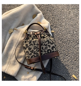 Detail view of leopard print bucket bag with leather trim and gold hardware accents