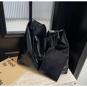 Detail view of large glossy black tote bag with matching pouch on marble surface