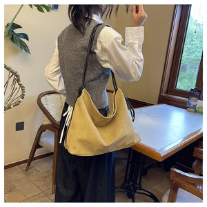 Détail du sac hobo jaune gingembre en daim avec fines bretelles et une texture souple et douce