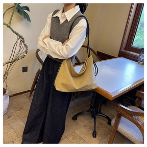 Grand sac cabas minimaliste en daim kaki avec bandoulières noires dans un café