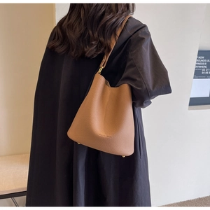 Vue arrière d'un mannequin portant un sac seau en cuir marron avec détails dorés