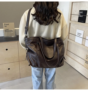 Detail showing the large coffee brown tote bag texture and long adjustable shoulder strap