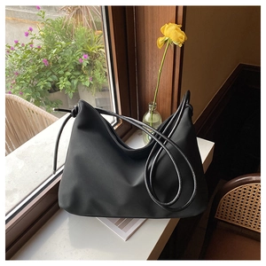 Vue détaillée d'un sac hobo noir minimaliste posé sur un rebord de fenêtre en bois