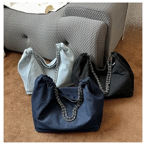 Detailed shot of large denim tote bags in black and blue with metal chain straps