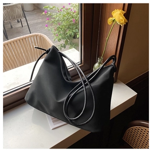Sac fourre-tout noir mat minimaliste en forme de croissant posé sur un rebord de fenêtre