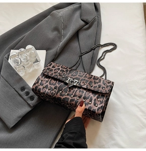 Détail du sac léopard avec clous argentés et bandoulière chaîne sur un blazer gris