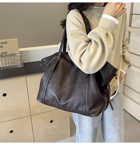 Detail of dark brown tote bag featuring vintage leather texture and star metal hardware