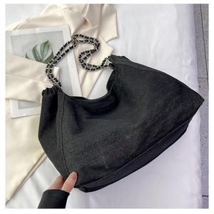 Detail of black denim hobo bag featuring silver chain strap and large capacity design