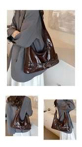 Detail view of a large dark brown high-gloss leather hobo bag with silver buckle accents