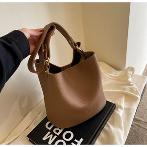 Détail du sac seau en cuir marron motif litchi avec finitions métalliques dorées
