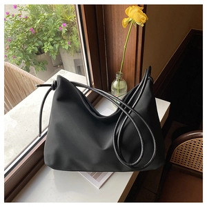 Détail d'un grand sac cabas en toile noir avec fines bretelles et finitions métalliques