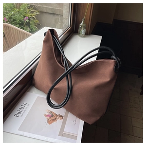 Vue détaillée d'un grand sac hobo en toile marron avec des anses en corde noire sur un rebord