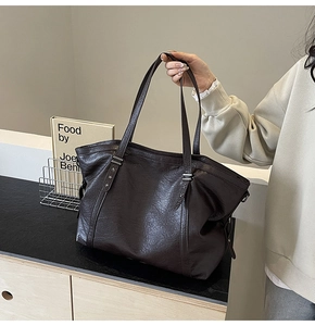 Detail of dark brown leather tote bag featuring star studs and pebble grain texture