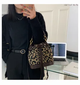 Detail of trendy leopard print bucket bag with brown leather trim and gold metal rings