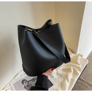Gros plan du sac seau en cuir noir grainé avec des boucles métalliques dorées chic