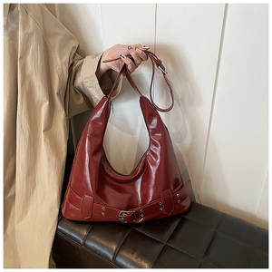 Detail view of burgundy patent leather hobo bag with bold buckle strap and silver eyelets