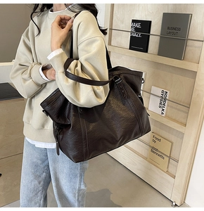 Detail of vintage brown leather tote bag showing side zipper and textured finish