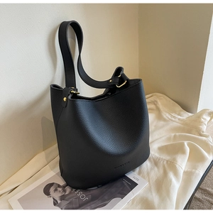Détail du sac seau en cuir grainé noir avec anneaux métalliques dorés et large anse