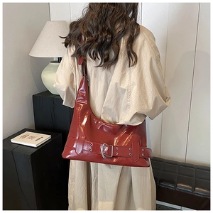 Close-up of glossy burgundy patent leather shoulder bag with metallic buckle detail