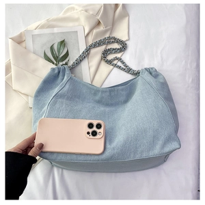 Detail showing high capacity of blue denim tote bag next to a mobile phone