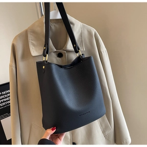 Détail du sac seau en cuir grainé noir avec boucle en métal doré et logo de marque