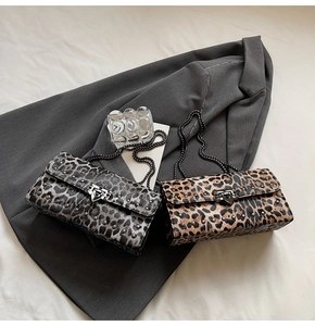 Détail de sacs bandoulière léopard avec clous métalliques et bandoulières chaîne sur costumes