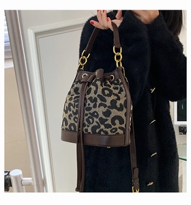 Detail of leopard print bucket bag with drawstring closure and golden hardware chain