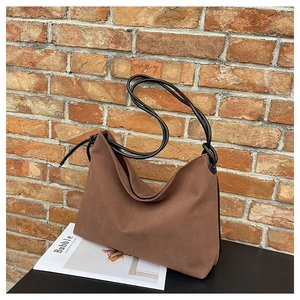 Détail d'un sac bandoulière en toile marron avec bandoulières à nœuds noirs de style rétro