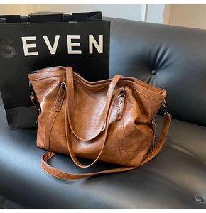 Detail of a brown retro tote bag featuring a star-shaped metal rivet and textured leather