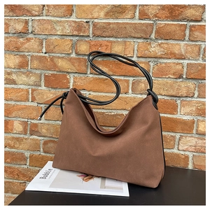 Détail du sac cabas en daim marron avec bandoulières en corde noire et nœuds décoratifs