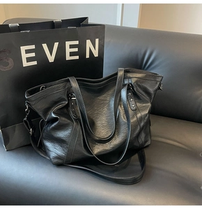 Detail view of black large tote bag showing faux leather texture and silver star rivet