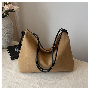 Détail du sac demi-lune en daim camel avec bandoulière en corde noire et embouts en métal