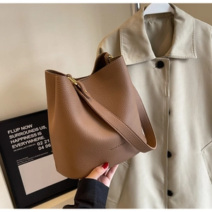 Détail du sac seau en cuir grainé marron foncé avec finitions métalliques dorées