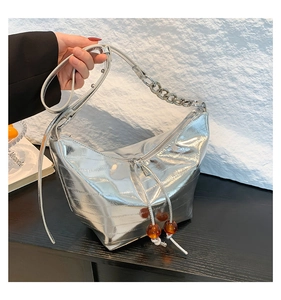 Detalle del bolso plateado de piel arrugada con cuentas de ámbar en la cremallera y cadena