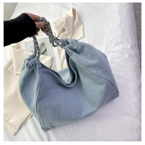 Detail showing denim tote bag with ruched design and silver metal chain shoulder strap