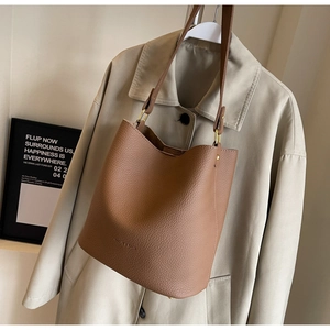 Détail de la texture cuir grainé marron et des finitions dorées d'un sac seau