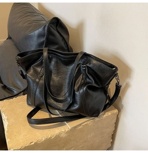 Detail of black tote bag featuring vintage leather texture and star-shaped metal rivets