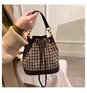 Detail of drawstring bucket bag with houndstooth pattern and gold chain decoration