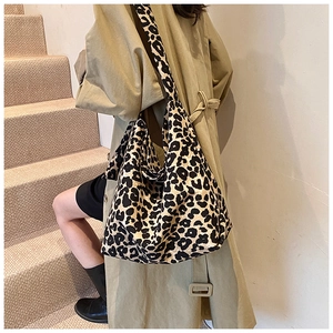 Leopard print canvas tote bag shown on shoulder of model wearing a trench coat